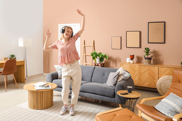 Young pretty woman in headphones dancing in stylish living room
