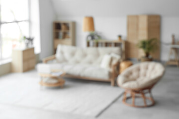 View of blurred living room with sofa, armchair and laptop on table