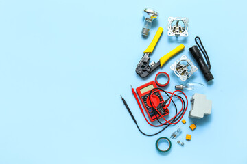 Electrician's tools, light bulb and electronics on blue background