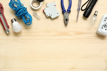 Electrician's tools, light bulbs and electronics on wooden background
