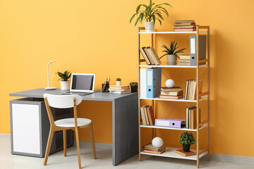 Stylish workplace with laptop near bookcase in stylish room