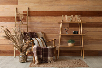 Chair with plaid, cushion, pampas grass and shelving unit in room