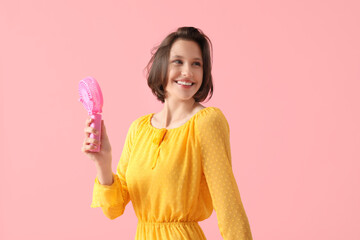 Young woman with small electric fan on pink background