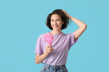 Young woman with pink portable electric fan on blue background