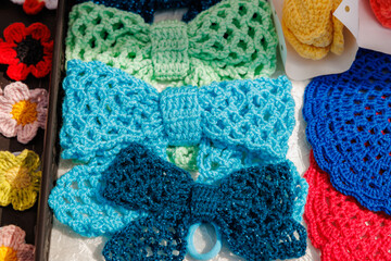 A table with a variety of knitted items, including a blue and green bow