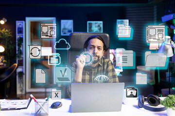 Portrait of man in home office doing business tasks on laptop, online connectivity concept. Freelancer using augmented reality tech to interact with files on notebook system, close up on icons