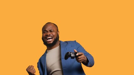 Joyous BIPOC gamer celebrating after winning gaming console game, studio background. Delighted man...