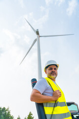 Engineer with drawing tube next to wind turbine