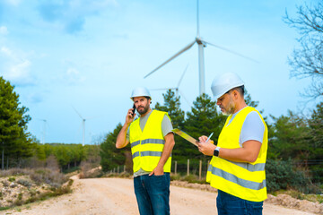 Engineers working in a green park next to wind turbines