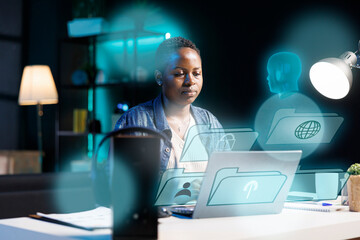 African american woman using laptop, interacting with artificial intelligence assistant using AR...