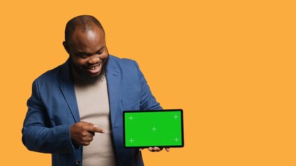 Upbeat african american man holding green screen tablet, doing recommendation. Cheerful BIPOC...