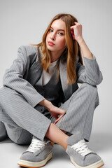 Young Woman in a Gray Suit Sitting on the Floor in Studio