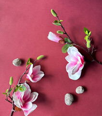 Elegant Magnolia Branches and Stones on Vibrant Red Background.