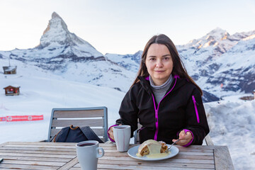 Woman enjoying fragrant mulled wine and slice of apple strudel topped with vanilla sauce in winter...
