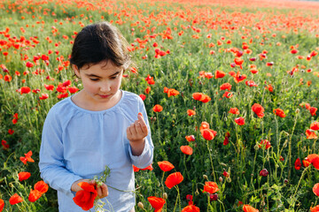 high angle view of girl standing in the field of poppies and tasting fresh peas