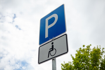 Parking sign for people with a disability. Summer day, clouds, blue sky, nobody. 
