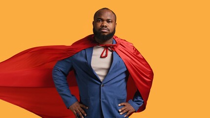 African american superhero flying with red cape, isolated over studio background, flexing muscles....
