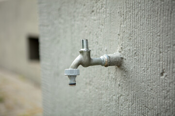 A faucet is attached to a wall. The gardening season can begin. nobody, concept. 
