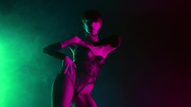 Dominatrix woman in bdsm corset dancing on stage in neon light. Mistress, fetish