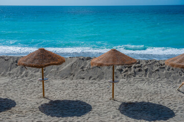 Straw umbrellas open on the rough beach