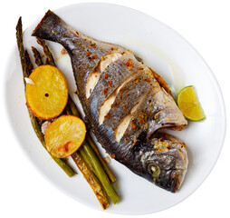 Plate with dinner of sea fish - fried dorado carcass, complemented with asparagus, baked potatoes,...
