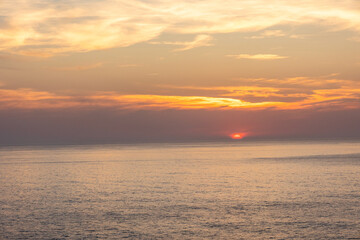 Landscape photo of dramatic, steep orange cliffs by the atlantic at sunset. Shot in Farol fo Cabo de Sao Vincente near Sagres, Portugal.