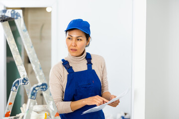 Female Asian engineer matching check list during repair works in house.