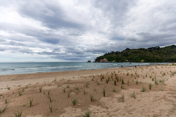People Enjoying Whangamata Beach Despite the Overcast Sky