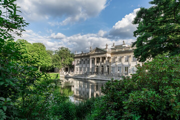 Classicist palace and park in Warsaw, Poland, Europe on sunny day with reflection in pond. - obrazy, fototapety, plakaty