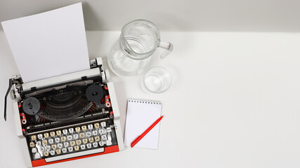 Vintage Russian letters typewriter with blank paper,glass of water and notepad on white background