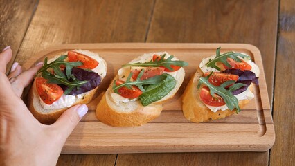 A woman carefully arranged bruschetta with cheese and tomatoes on table Enjoy the delicious blend of cheese and juicy tomatoes stop crunchy bread creating a mouth Indulge in rich flavors of bruschetta