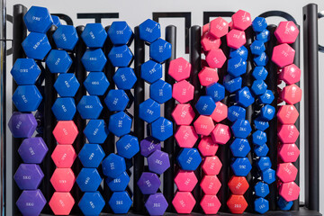 A stand with dumbbells of different weights and colors for sports training