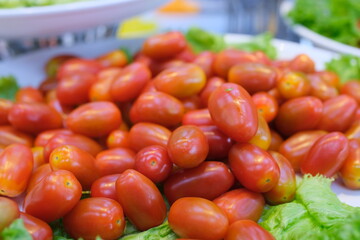 small tomatoes on a plate Red small cherry tomatoes in a bowl on white background, top view