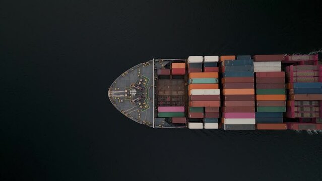 Top view large cargo ship cruising on water, its deck crammed with shipping containers. Container ship is the workhorse of global trade, designed to efficiently transport goods over vast distances.