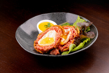 scotch egg Meat cutlet with boiled egg, pieces on a dark wooden background. Mini meat rolls. Scottish cutlet.