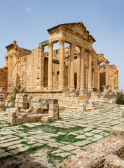 Fototapeta premium Scenic view of ancient Roman forum at Sbeitla archaeological site in Tunisia with majestical ruins of temple dedicated to Capitoline Triad - Jupiter, Juno, and Minerva on spring day