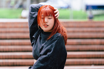 Passionate Korean dancer with red hair in the flow of her routine in an urban outdoor setting