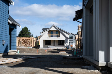 Various stages of new homes under construction in a cottage community on a sunny spring day,...