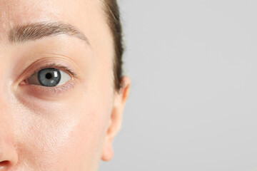 Closeup photo of woman with beautiful eyes on light background. Space for text