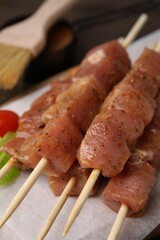 Skewers with cut raw marinated meat on wooden table, closeup