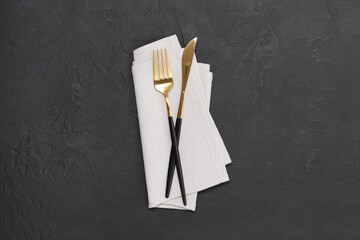 Beautiful cutlery set and kitchen towel on black table, top view