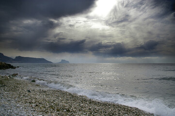 Dia de tormenta en el Mediterráneo, nubes que amenazan dejando pasar la luz, montaña junto al...