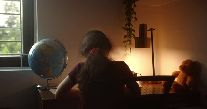 Child is studying. School girl studying at home, taking notes, doing homework. Back view child doing homework. Little girl studying at home. Portrait of a handsome cute child doing homework at home.4K