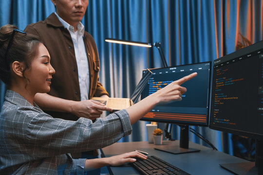 IT developers discussing with point to intelligent website development coder system running data online two screens information technology at neon light room at modern office. Infobahn.