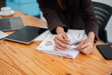 Close-up of a detail-oriented professional's hands meticulously organizing business reports and...