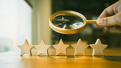 A magnifying glass and 5 stars arranged on a table, a review, rating and survey concepts.