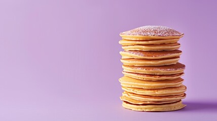 Stack of pancakes with powdered sugar on purple background