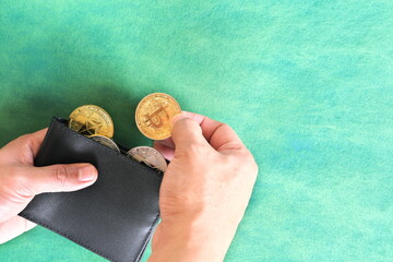 Human hand holding black wallet with crypto coins inside. Cryptocurrency use for payment concept.