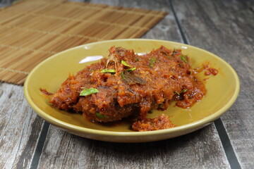 Deep Fried gourami fish dressing with spicy red curry sauce serving on the plate. Famous hot and spicy seafood menu in Thai cuisine.