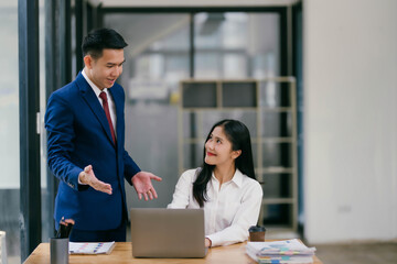 A man and a woman are sitting at a desk with a laptop in front of them